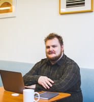 man sitting on sofa using laptop