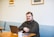 man sitting on sofa using laptop
