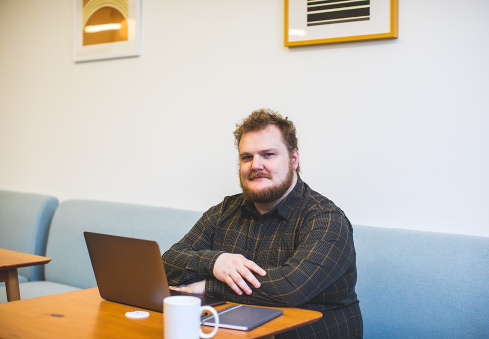 man sitting on sofa using laptop