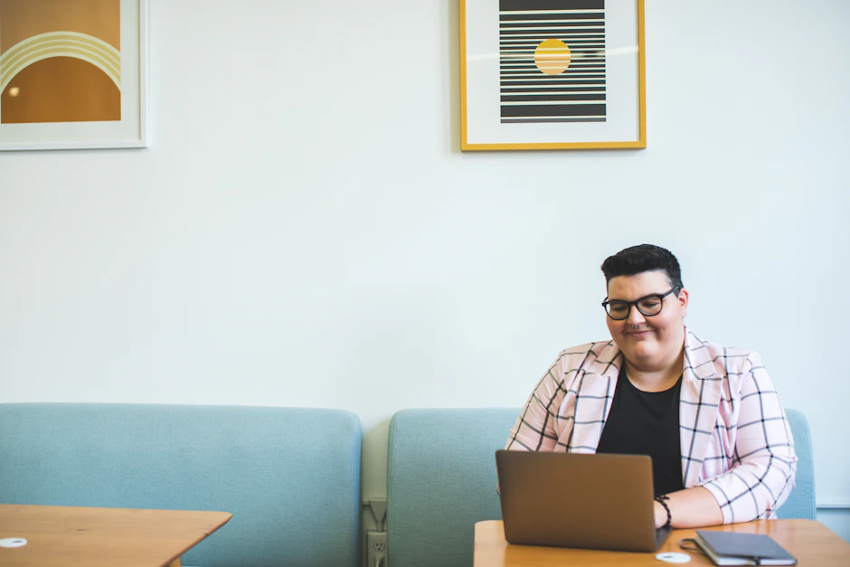 Person smiling while working at a laptop in a bright office