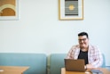 smiling man sitting on chair using laptop
