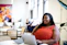 A confident young woman smiling while working on a laptop in a modern office.