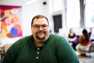 smiling man in green polo shirt wearing eyeglasses