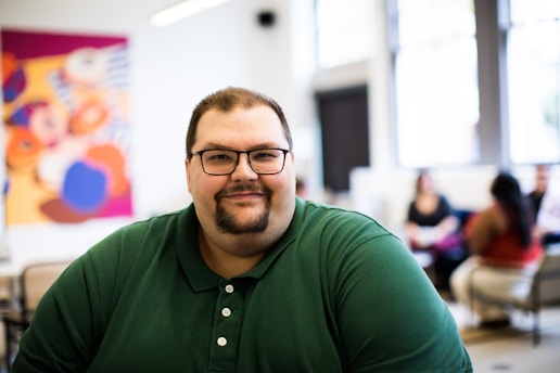 smiling man in green polo shirt wearing eyeglasses