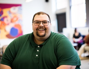 man sitting down wearing green polo shirt