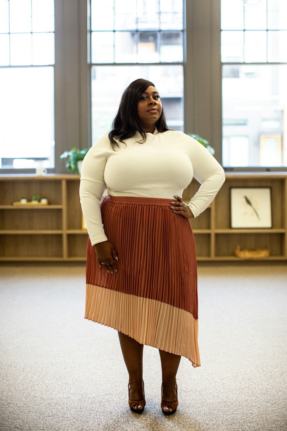 woman wearing white sweatshirt and red and brown accordion skirt