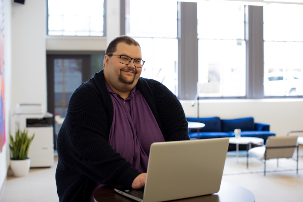 man sitting on chair near table using laptop computer