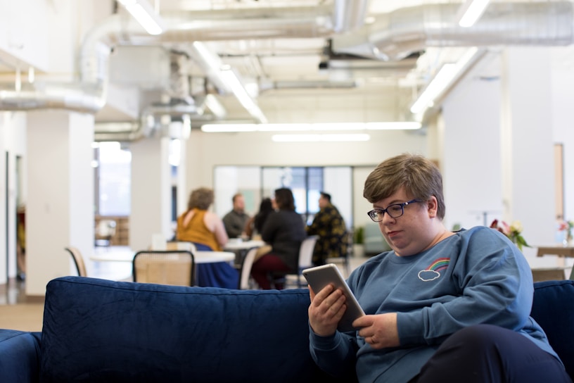 woman holding tablet computer sitting on blue couch