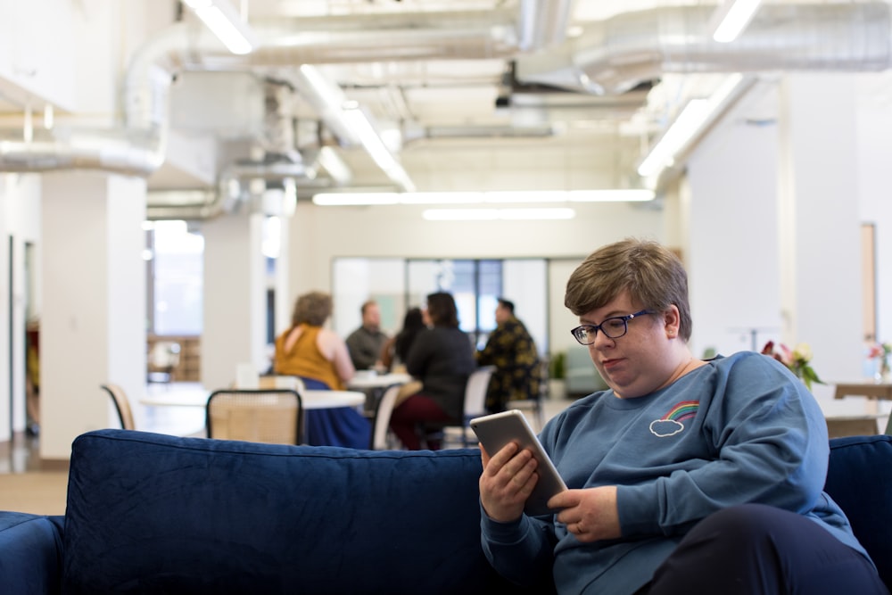 woman holding tablet computer sitting on blue couch