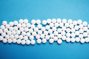 A collection of small, white, round tablets arranged neatly against a bright blue background.