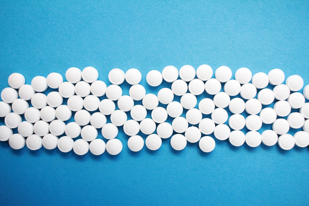 Un gruppo di pillole bianche sedute sopra una superficie blu