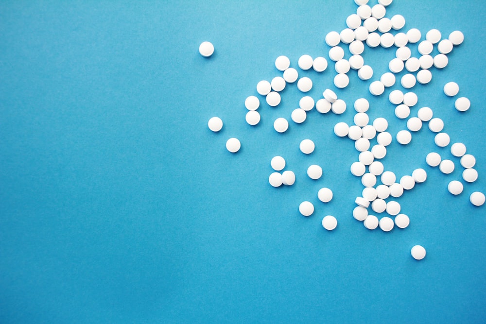 une pile de pilules blanches posée sur une table bleue