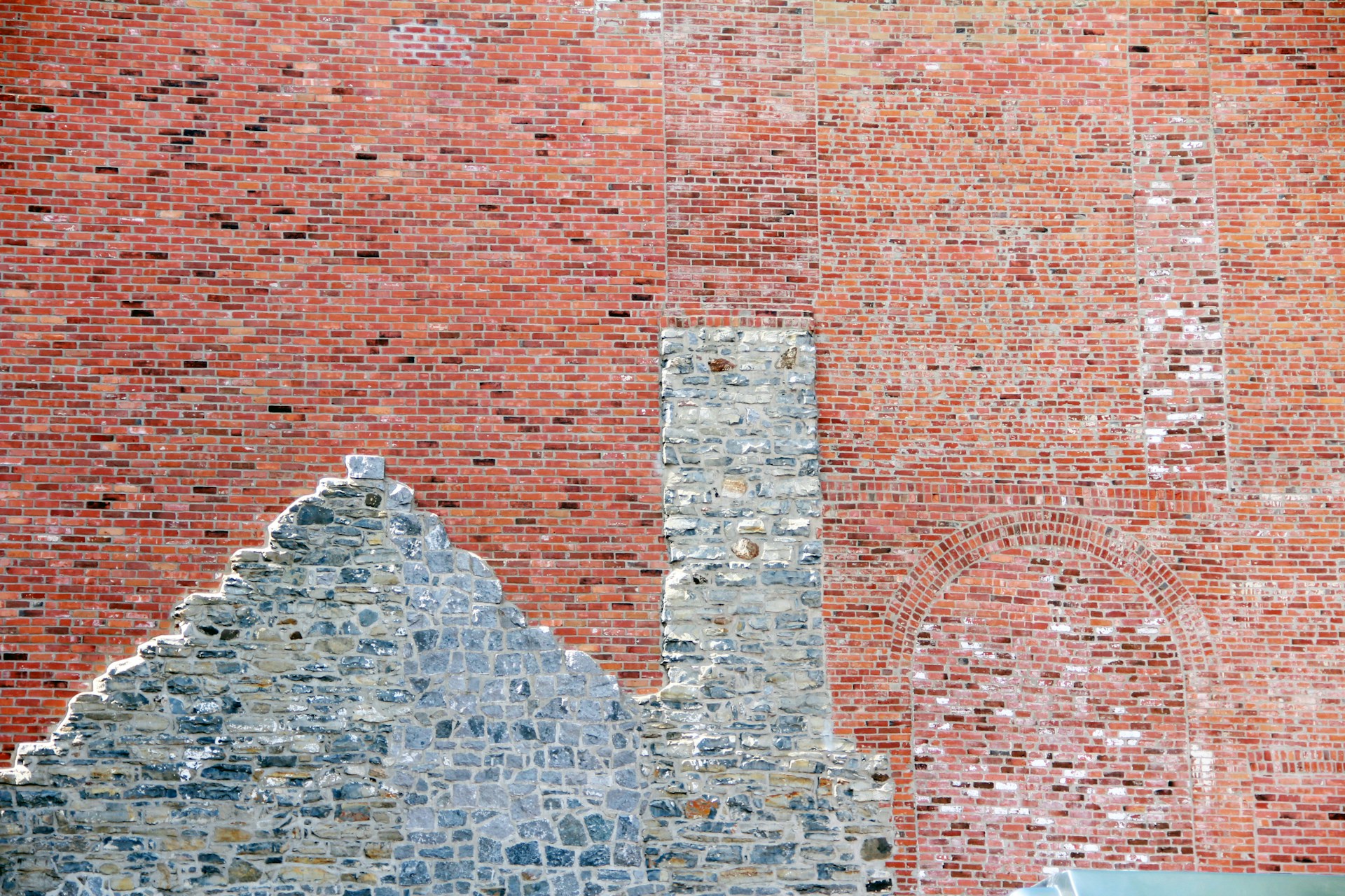a person sitting on a bench in front of a brick wall