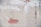A worn plaster wall with areas of exposed red brick, configured in irregular shapes. Some sections have remnants of painted white clouds atop the plaster, contributing to an abstract artistic feel.