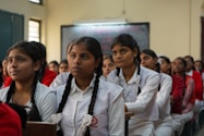 A group of smiling girl students in a bright classroom, engaged in a lively science experiment.
