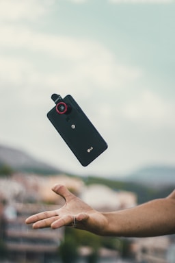 A person reaching out with a smartphone in hand.