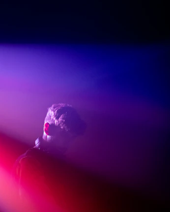 Atmospheric photo of Jaiden immersed in music, shadows and light blending fluidly around him.