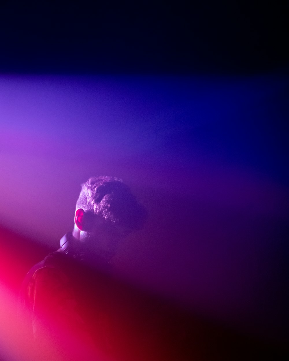 a man standing in front of a purple and red light