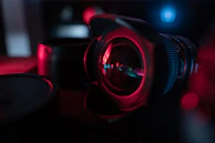 A close-up of a camera lens reflecting the studio lights and a focused photographer.