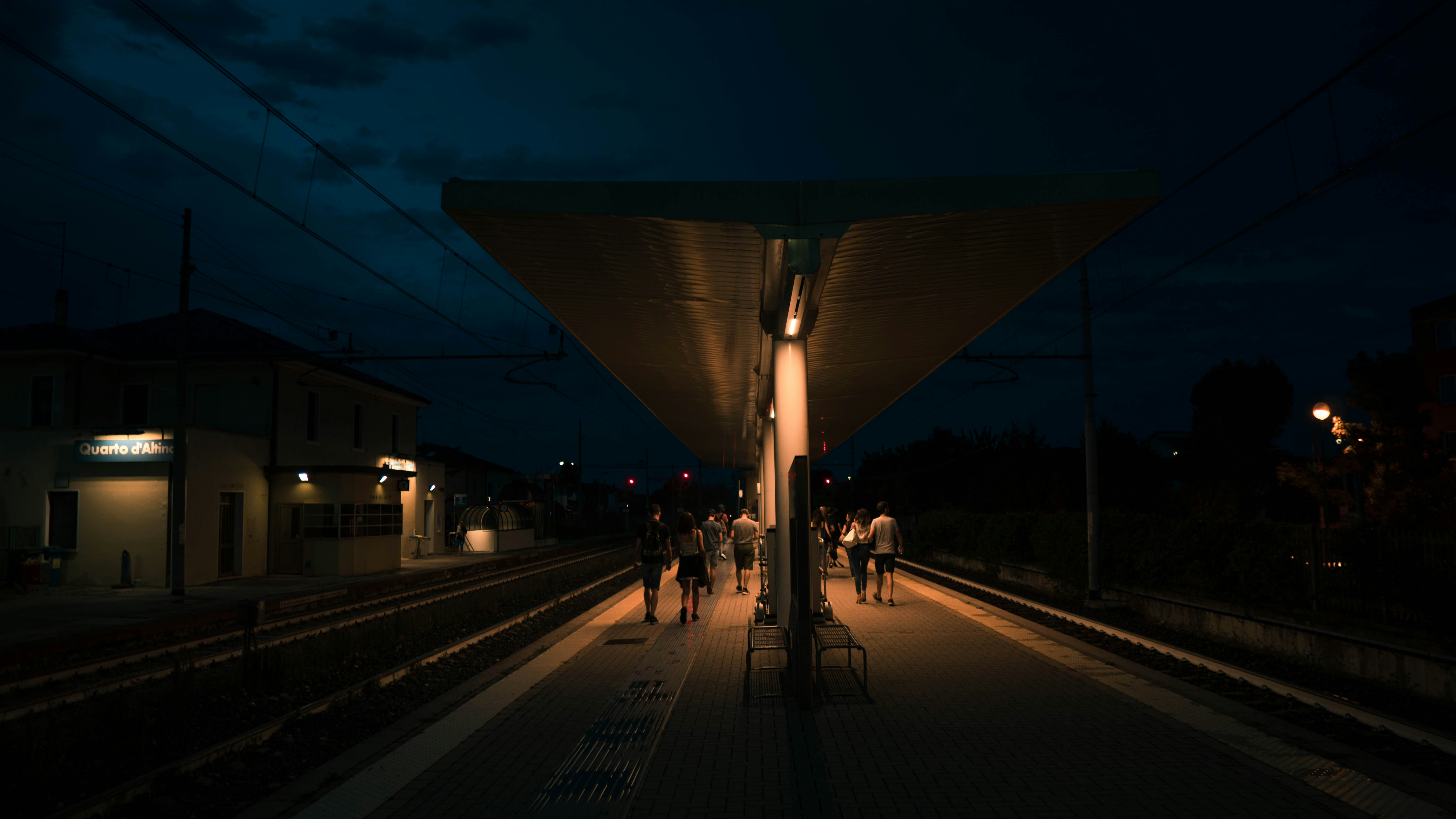people walking on road during nighttime, Train station at night in Italy