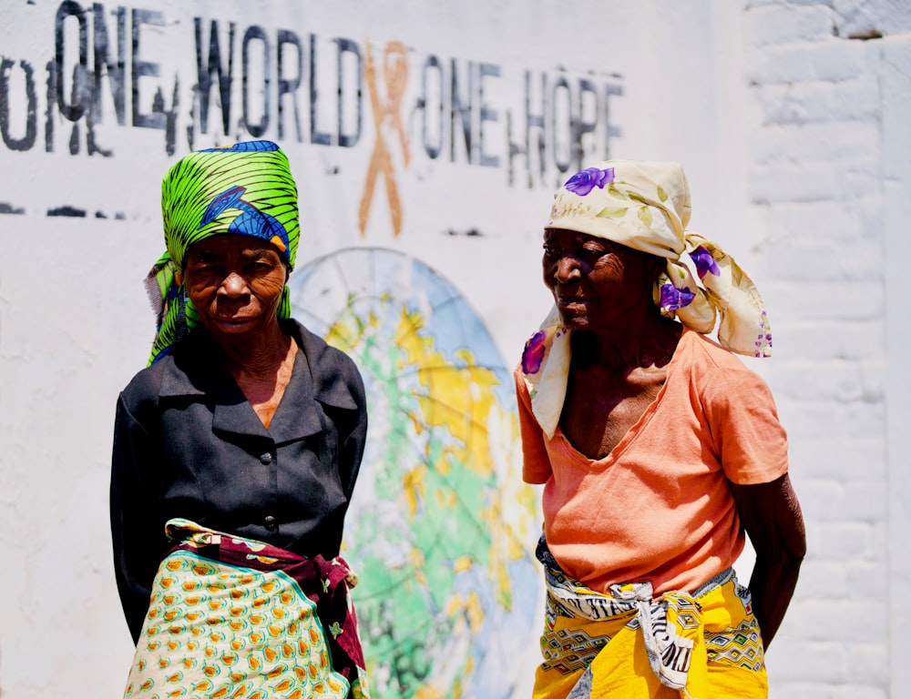 close-up photography of two women standing next to white wall