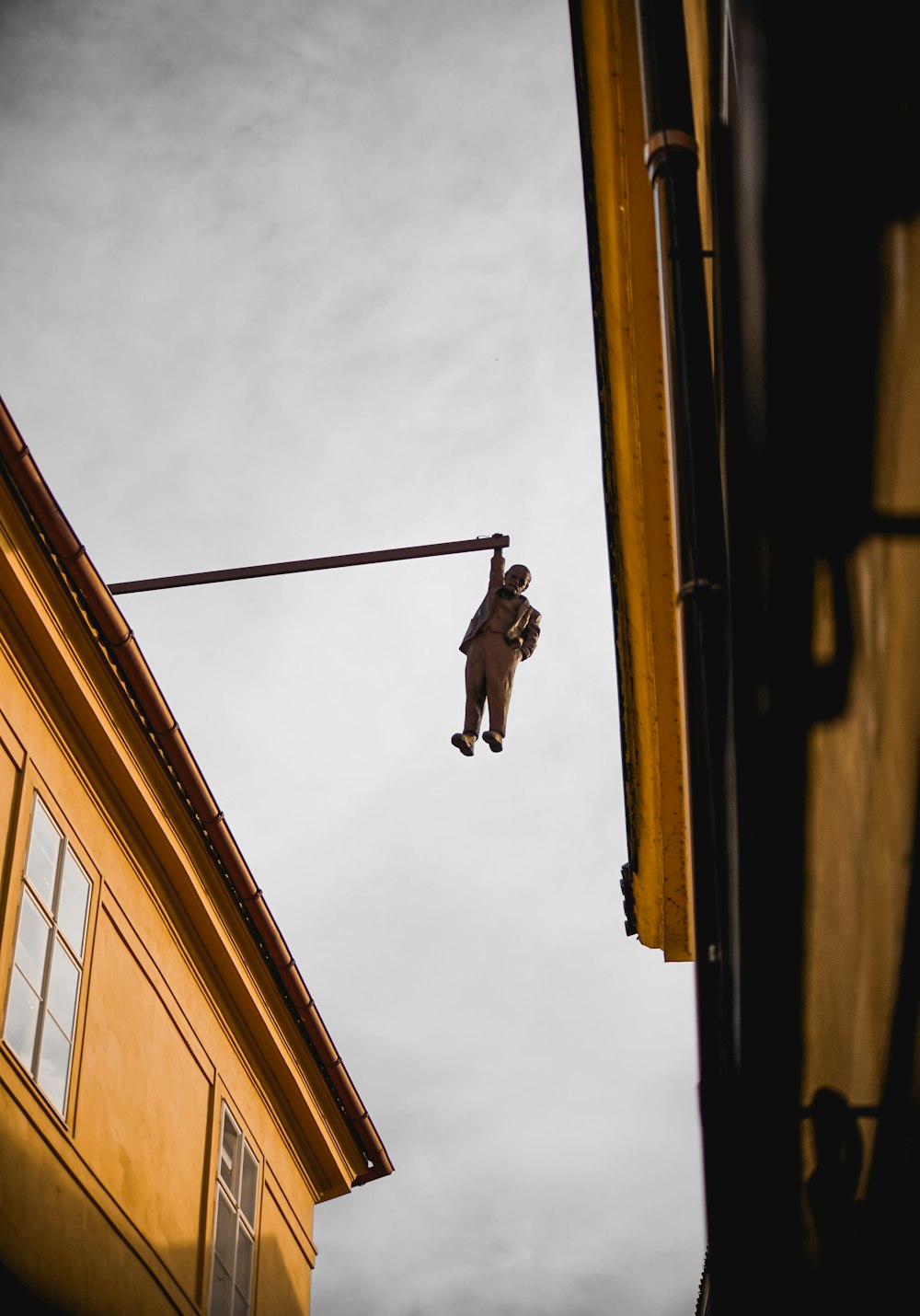 low-angle photography of statue of person hanging on rail during daytime
