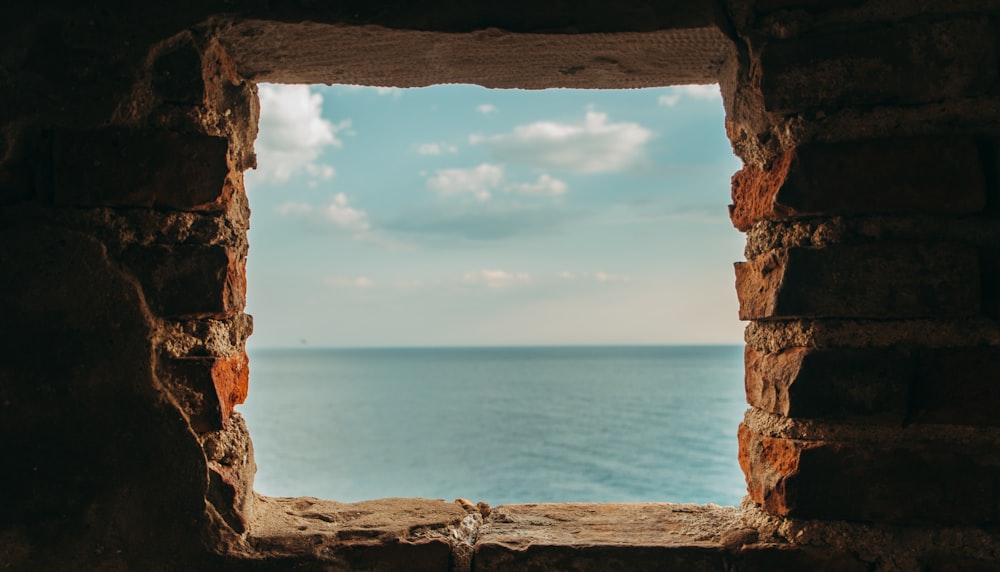 Vue sur la mer bleue depuis une fenêtre carrée en pierre