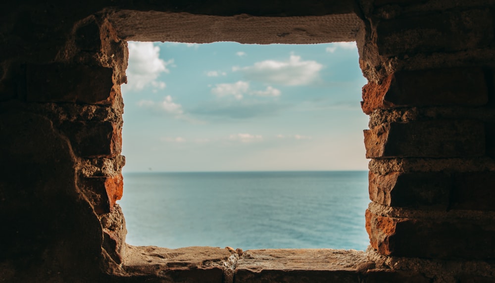 Blick auf das blaue Meer aus einem quadratischen Steinfenster