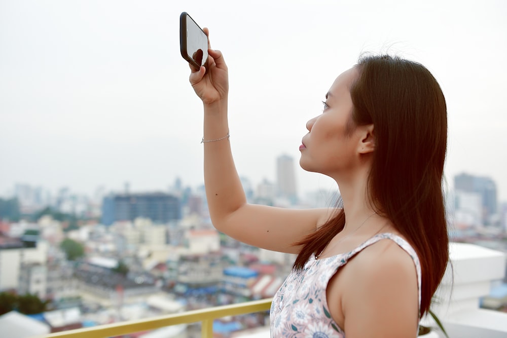 close-up photography of woman taking photo using smartphone