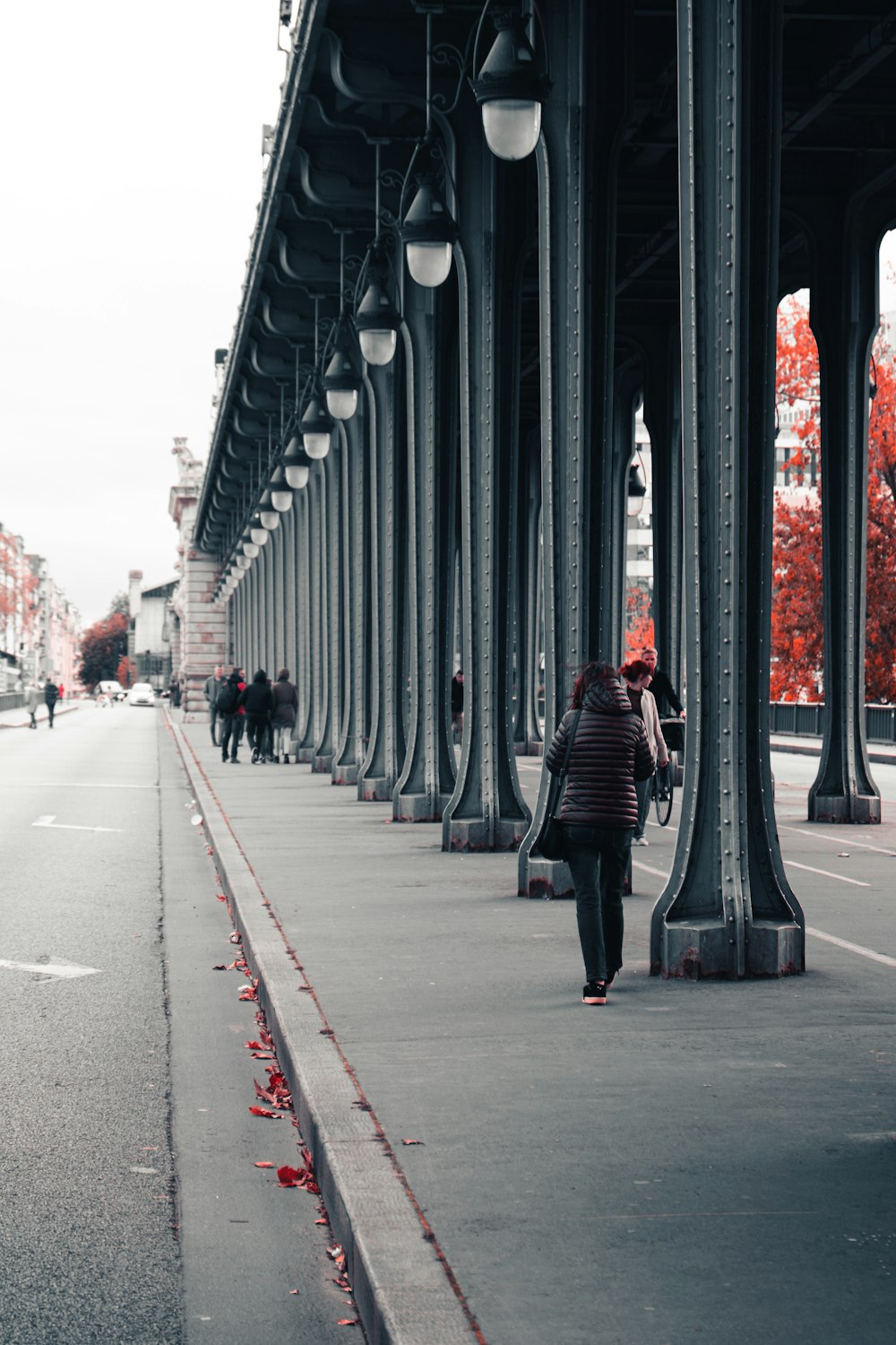 people walking beside road under bridge during daytie