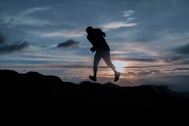A filmmaker capturing an athlete mid-action with a glowing sunset in the background.