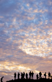 A group of diverse individuals standing united on a hilltop at sunrise, symbolizing strength and unity.