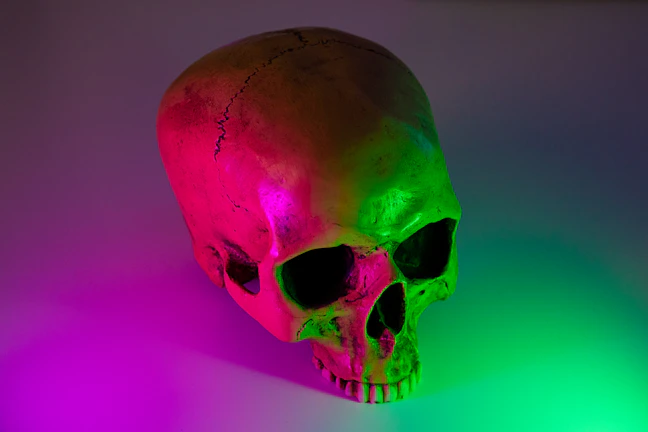 Close-up of a vibrant neon skull tattoo glowing under studio lights.