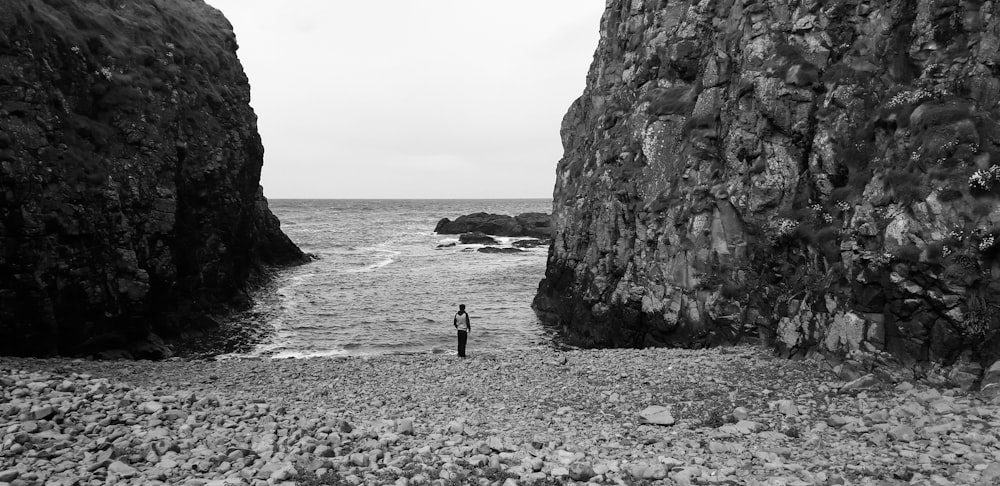 gray-scale photo of man near body of water