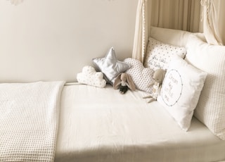 plush toys and throw pillows on bed with comforter