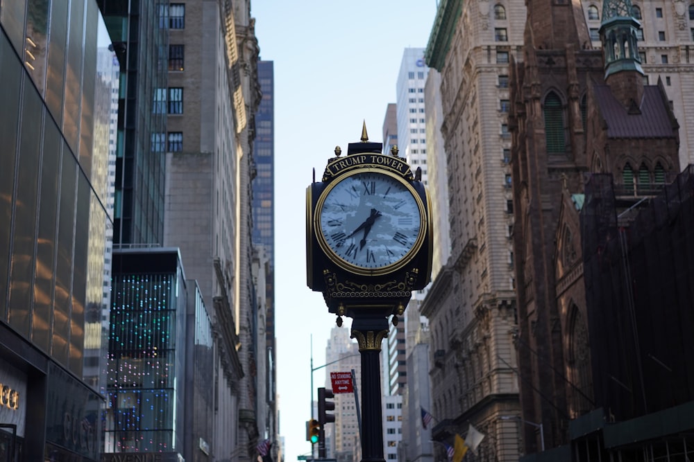 white and black clock pole in middle of street near buildings