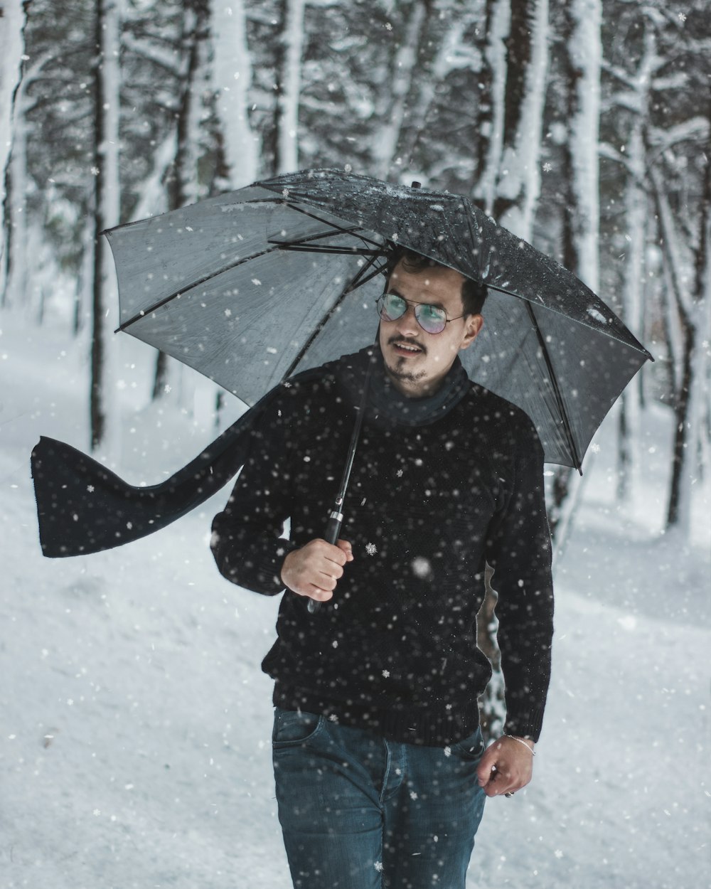 man holding umbrella outdoor during snowfall