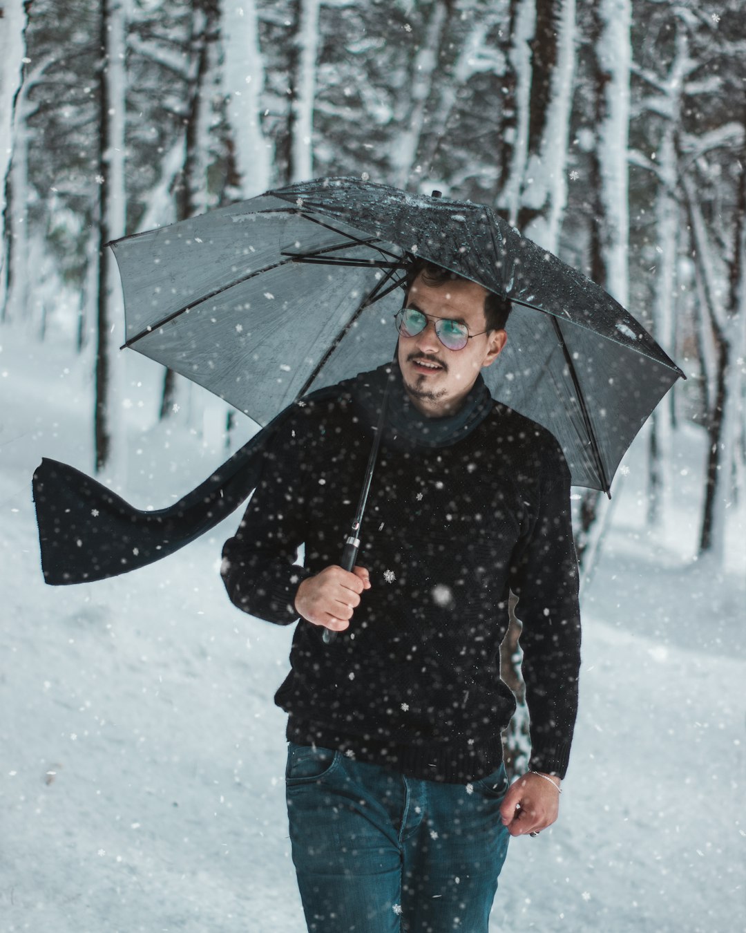 man holding umbrella outdoor during snowfall