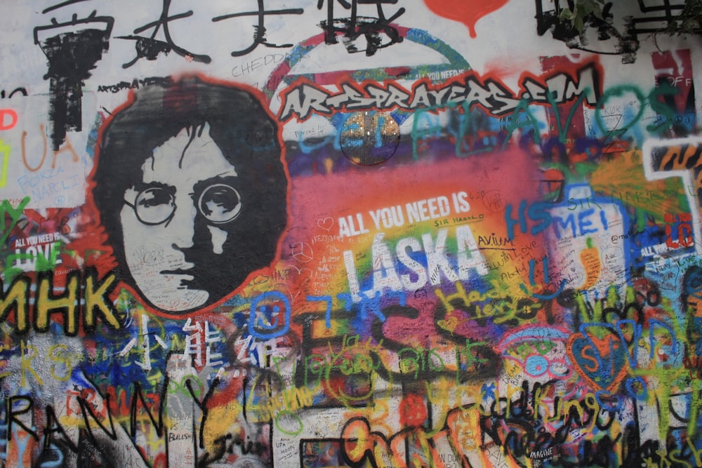 Un mur couvert de beaucoup de graffitis avec une photo d’un homme
