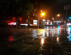 A city street scene with gentle rain and reflections on the pavement