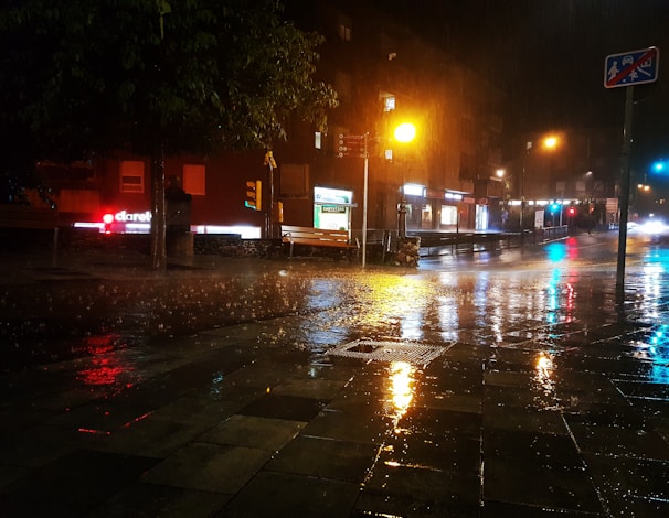 Cinematic still from a short film showing a rainy street scene at night