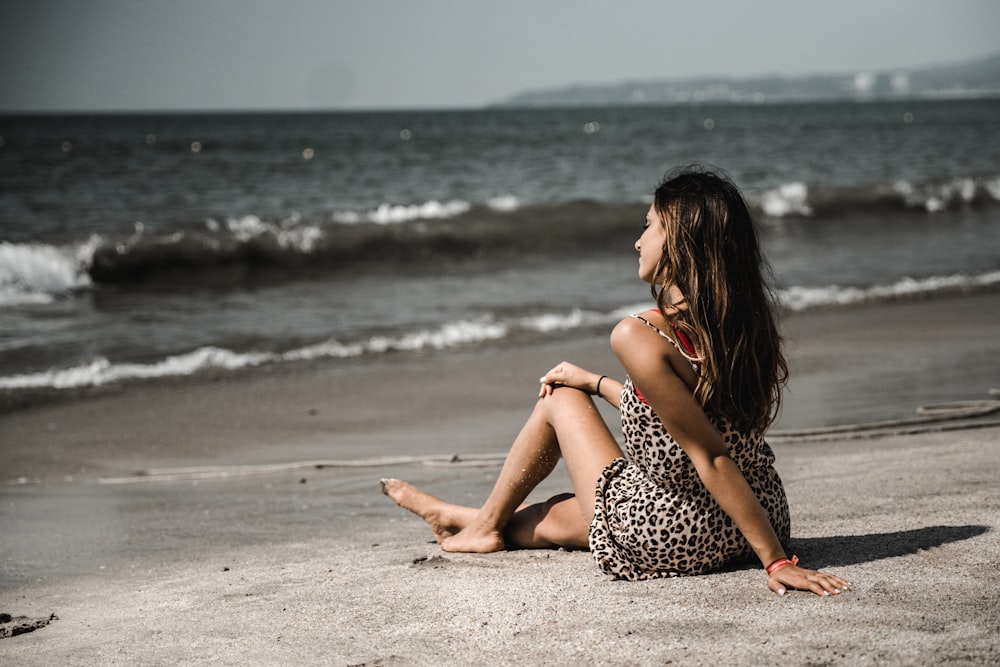 woman sitting on sand at beach