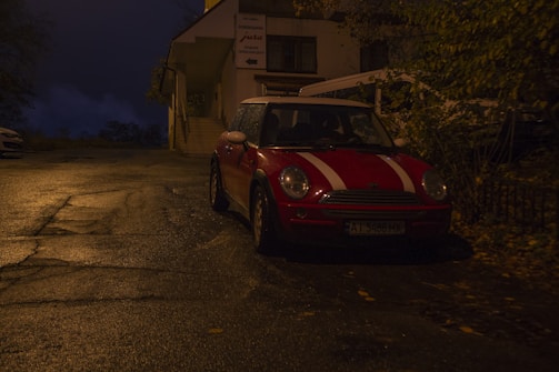 A sleek red MINI 3 Door parked on a city street at sunset.