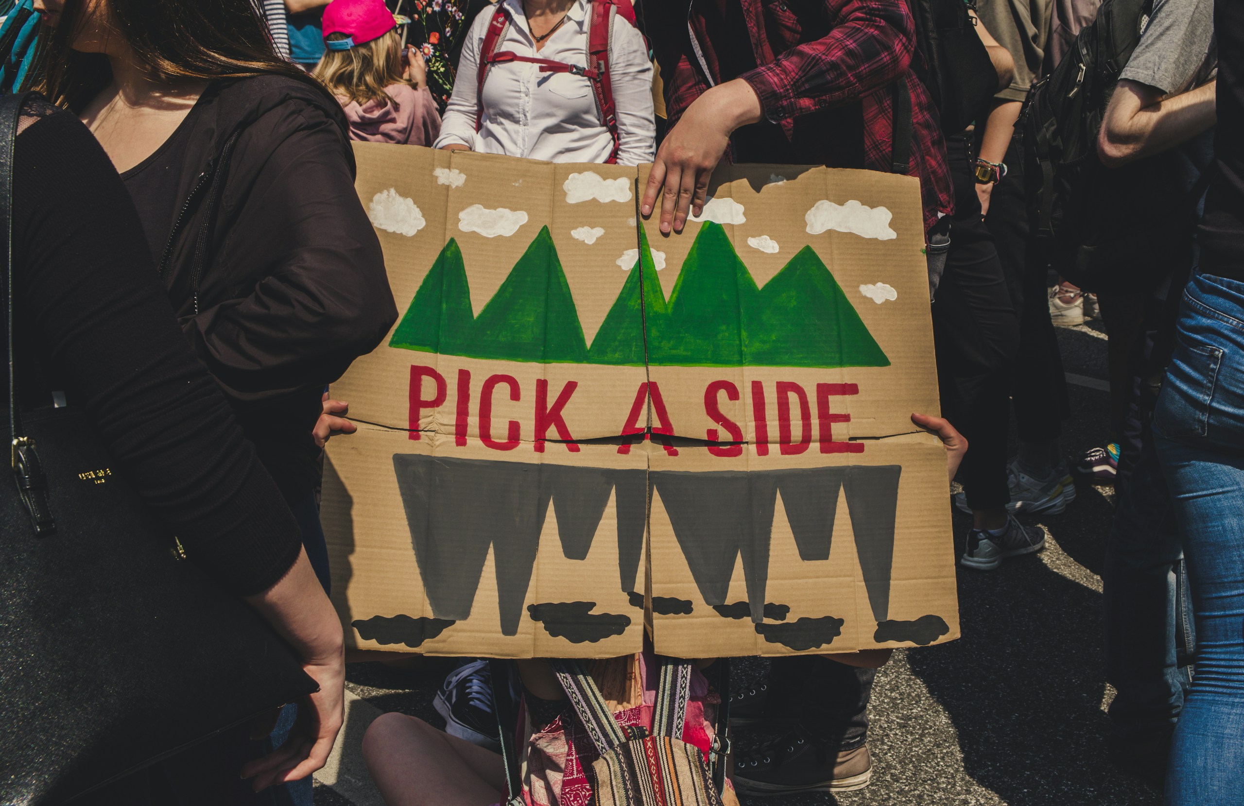 people protesting with sign "pick a side"
