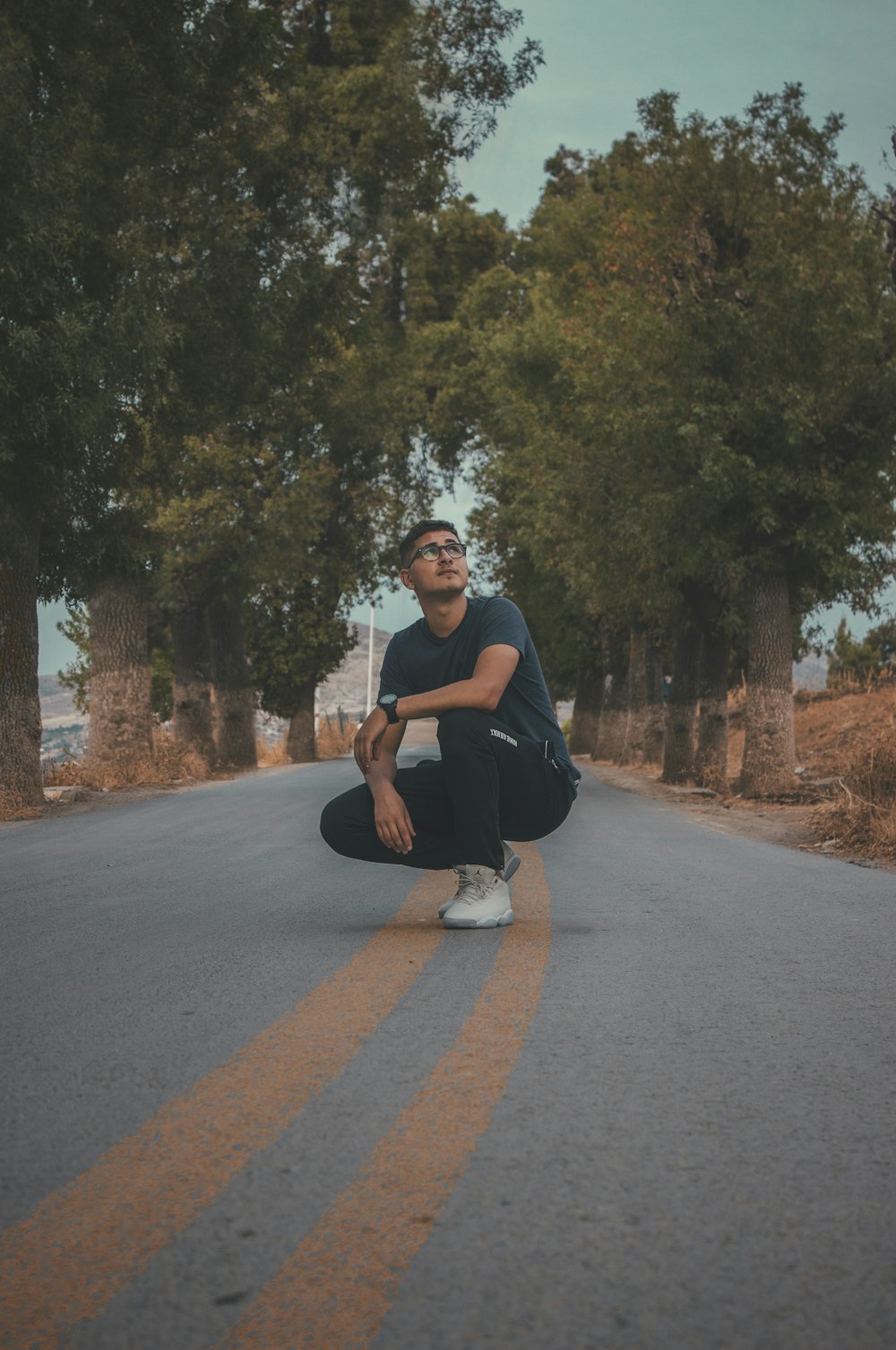 man crouching in middle of road