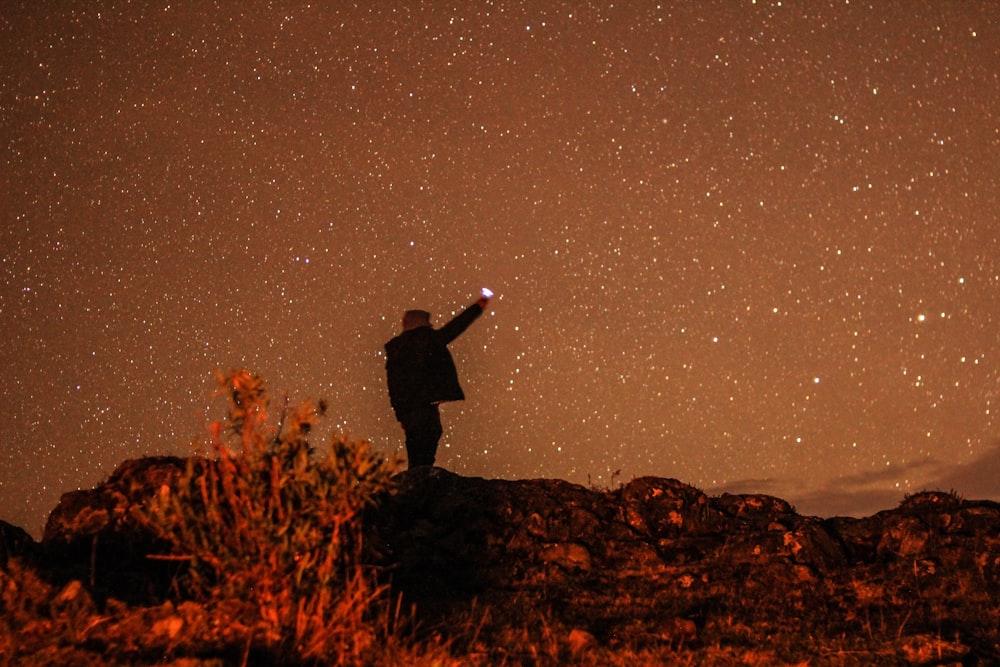 uomo in piedi sulla collina durante la notte