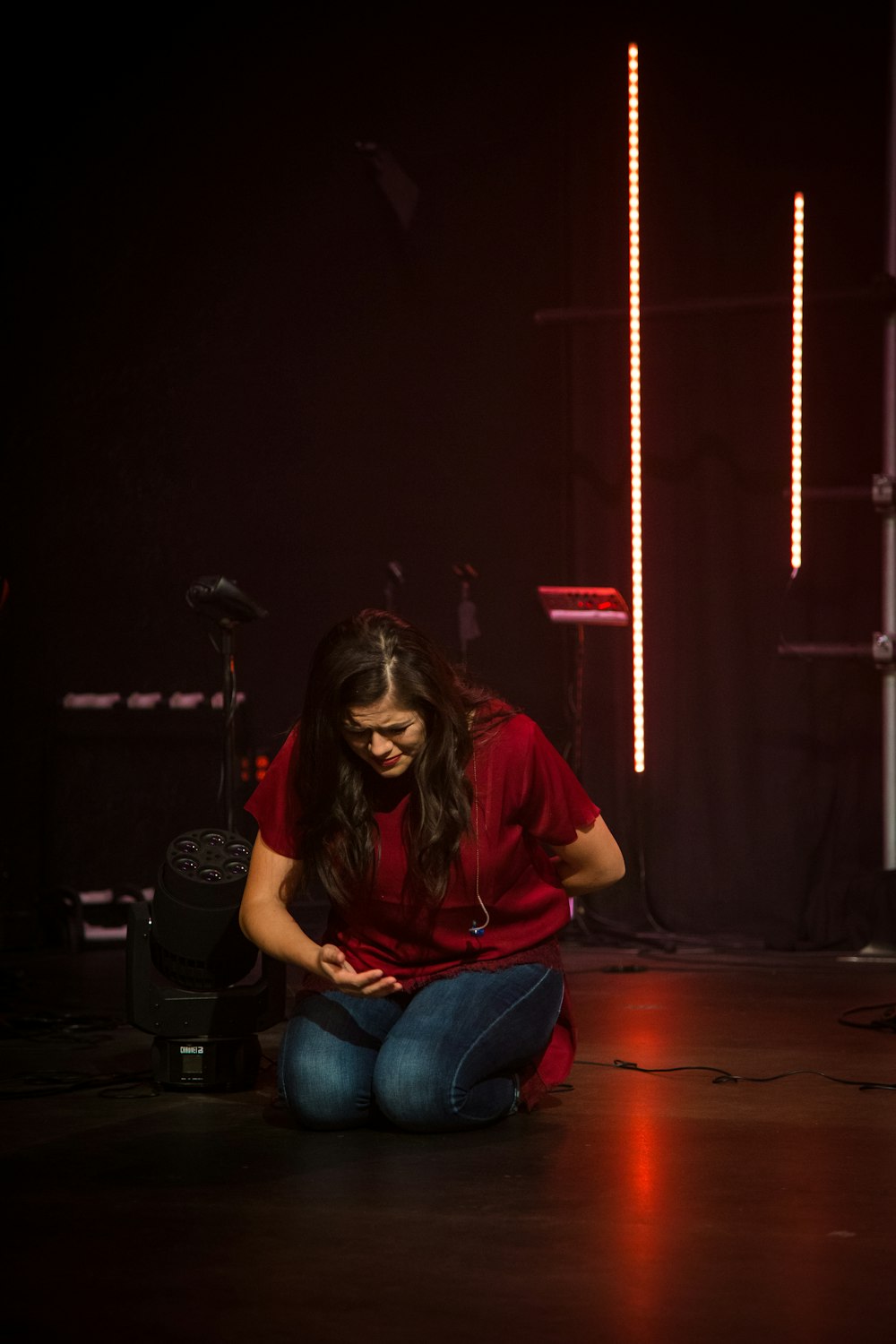 woman wearing red shirt and blue denim jeans kneeling on ground