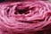 A close-up view of a ball of yarn in shades of pink and purple. The texture of the yarn fibers is clearly visible, showing intricately woven threads.
