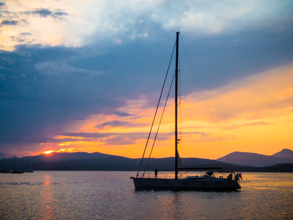 sailboat on calm body of water under golden hour