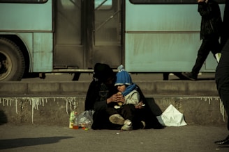 person feeding toddler sitting near the road at daytime